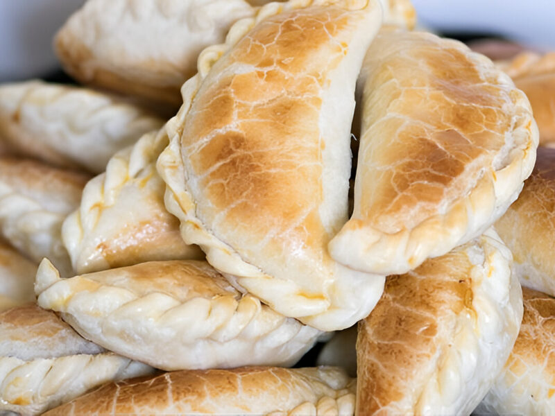 Empanadas de carne jugosas sobre tabla de madera, con relleno visible