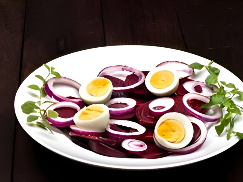 Ensalada de remolacha y huevo duro con cebolla y perejil, servida en plato blanco