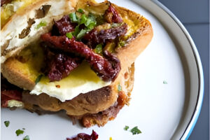 Tostada francesa rellena con tomate fresco y queso fundido, dorada y crujiente por fuera