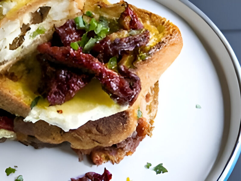 Tostada francesa rellena con tomate fresco y queso fundido, dorada y crujiente por fuera