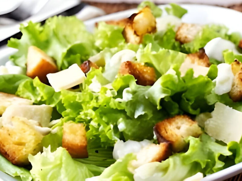 Ensalada César con trozos de pollo grillado, crutones crujientes, lechuga romana y aderezo cremoso