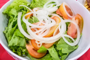 Plato de ensalada mixta con lechuga, tomate, cebolla y zanahoria rallada
