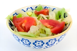 Ensalada simple casera con tomate, lechuga , servida en plato blanco