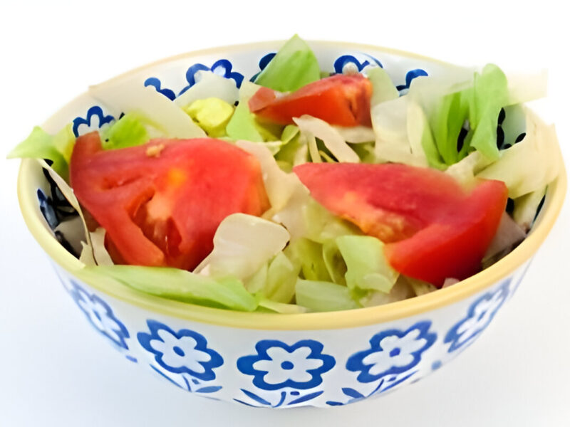 Ensalada simple casera con tomate, lechuga , servida en plato blanco