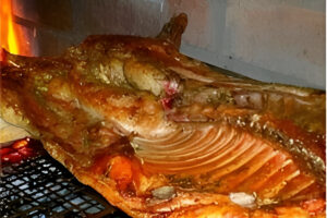 Lechón a la parrilla dorado y crujiente cocinado a fuego lento sobre brasas