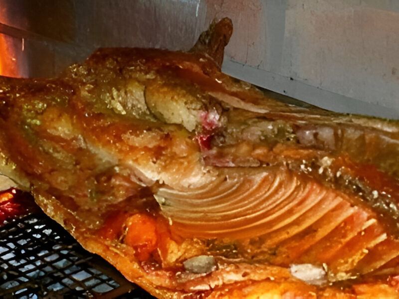 Lechón a la parrilla dorado y crujiente cocinado a fuego lento sobre brasas