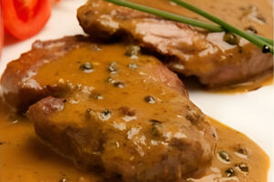 Medallones de lomo a la pimienta con salsa cremosa servidos en un plato
