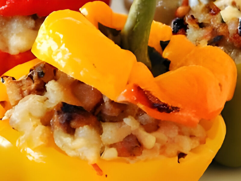 Pimientos rojos rellenos con carne, arroz y vegetales asados al horno, servidos sobre una fuente rústica