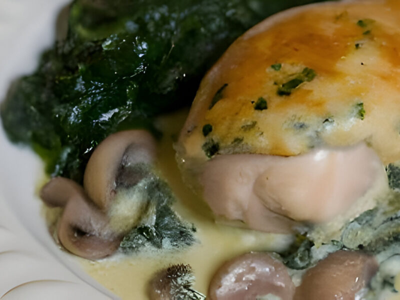 Pechuga de pollo rellena de champiñones y espinacas, bañada en salsa cremosa, servida con hierbas frescas