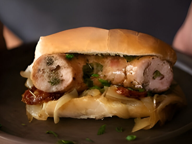 Choripán argentino con chimichurri servido en pan casero, acompañado de papas fritas y una bebida fría