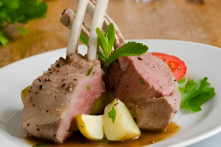 Plato de cordero a la menta servido con salsa verde y guarnición de verduras asadas