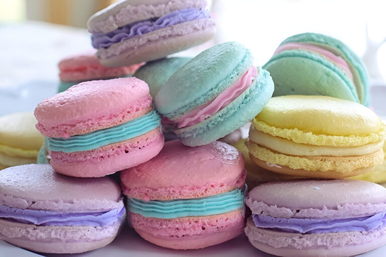 Macarons caseros de colores pastel con relleno de crema, dispuestos sobre una bandeja elegante