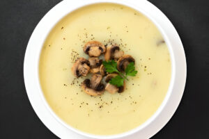 Sopa crema de champiñones servida en plato hondo con perejil fresco