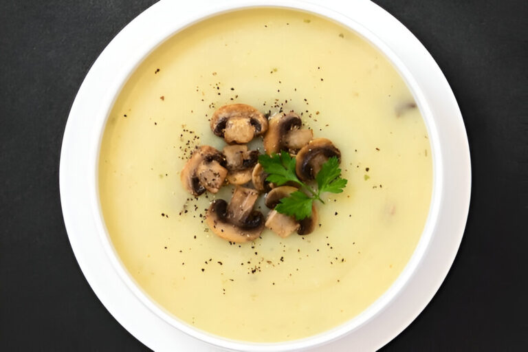 Sopa crema de champiñones servida en plato hondo con perejil fresco