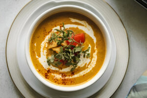 Sopa crema de cúrcuma servida con perejil fresco