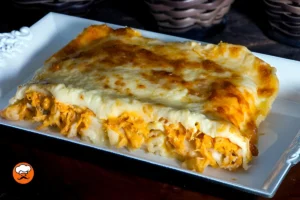 Porción de lasaña de pollo con abundante mozzarella gratinada