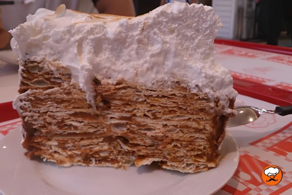 Porción de torta Rogel casera con capas finas, dulce de leche y merengue italiano