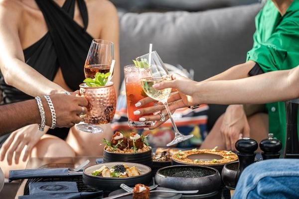 Personas compartiendo aperitivos y bebidas durante una reunión con amigos.