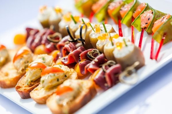 Selección de aperitivos internacionales variados servidos para compartir con salsas.