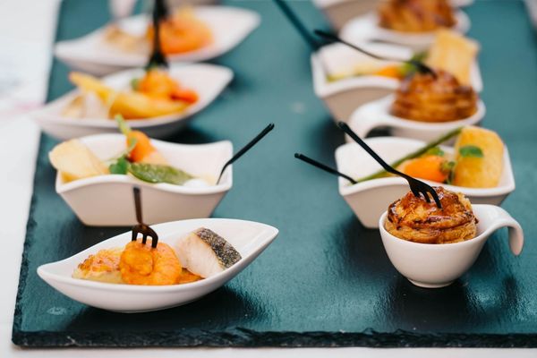 Aperitivos y entradas variados servidos en pequeñas porciones individuales sobre una bandeja.